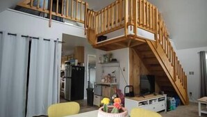 Uma sala de estar ampla com escada de madeira que dá acesso a um andar superior.