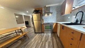Una cocina moderna con una mesa de madera, horno empotrado y un refrigerador grande.