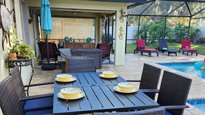 An outdoor patio with a dining table, chairs, and a pool.