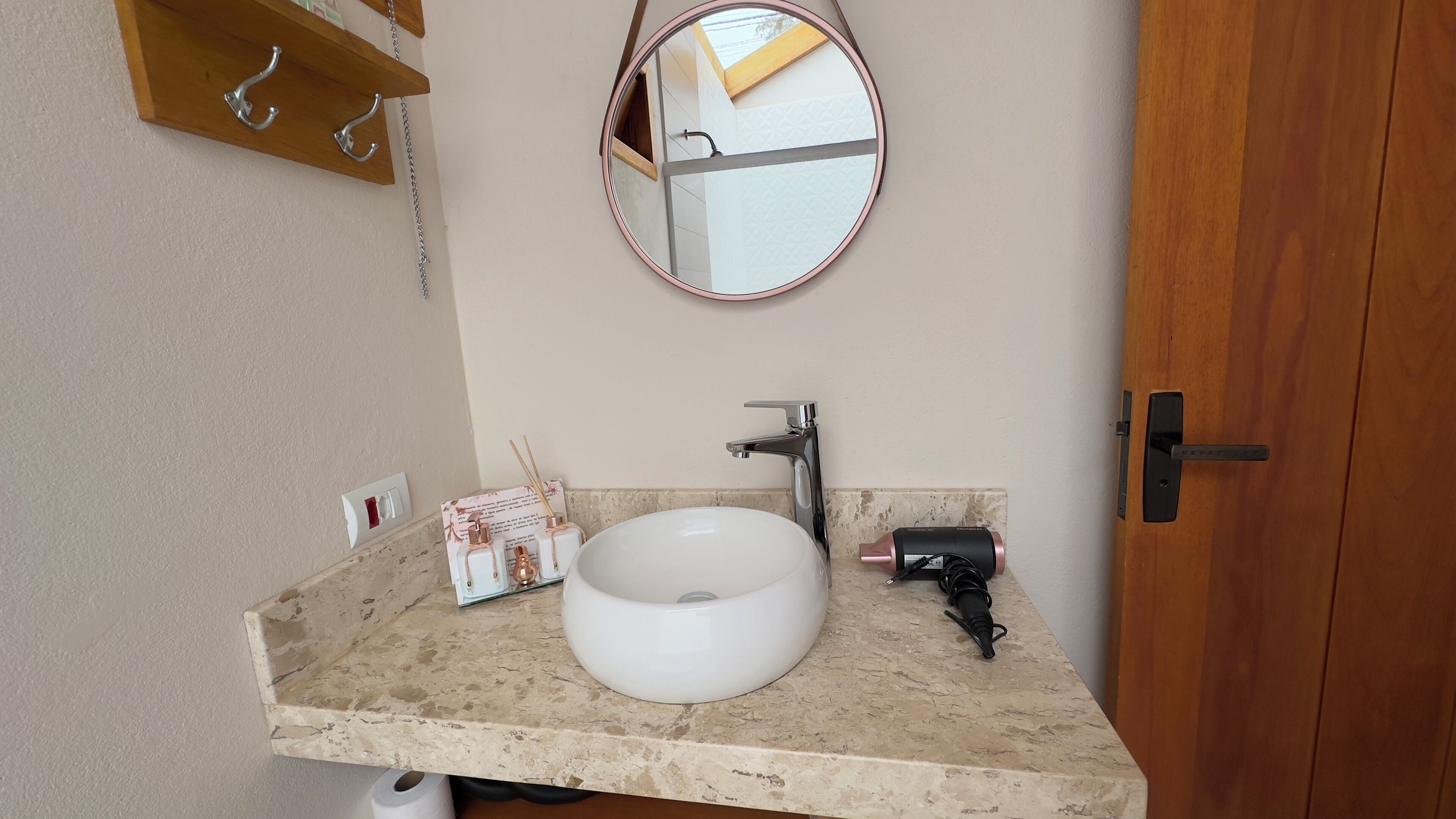 A bathroom with a white sink, a mirror, a towel rack, and a toilet paper holder.