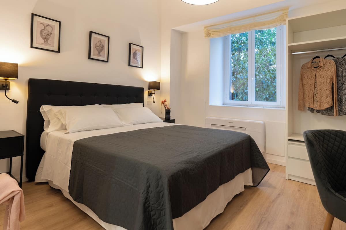 A bedroom with a bed, bedside tables, a window with a view, and a wardrobe.