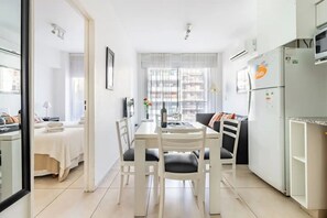Enjoy a bright and inviting space with a dining area, sofa, and refrigerator, perfect for relaxing and recharging.