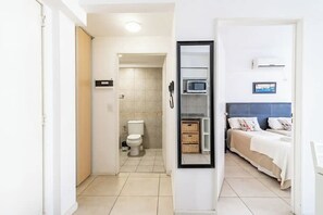 Enjoy a clean and functional space with a neatly arranged bed, compact bathroom, and wall-mounted air conditioning unit.