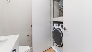 Ein kleines Badezimmer mit Toilette, Waschmaschine und einem kleinen Schrank.