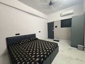 A modern bedroom with a bed, a wardrobe, a door, and an air conditioning unit. - Aqua Stays (Mumbai)
