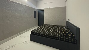 Un dormitori amb un llit, un ventilador de sostre, una làmpada i una porta.