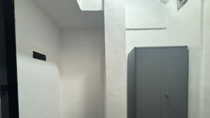 Passadís estret amb un armari gris i una porta blanca.