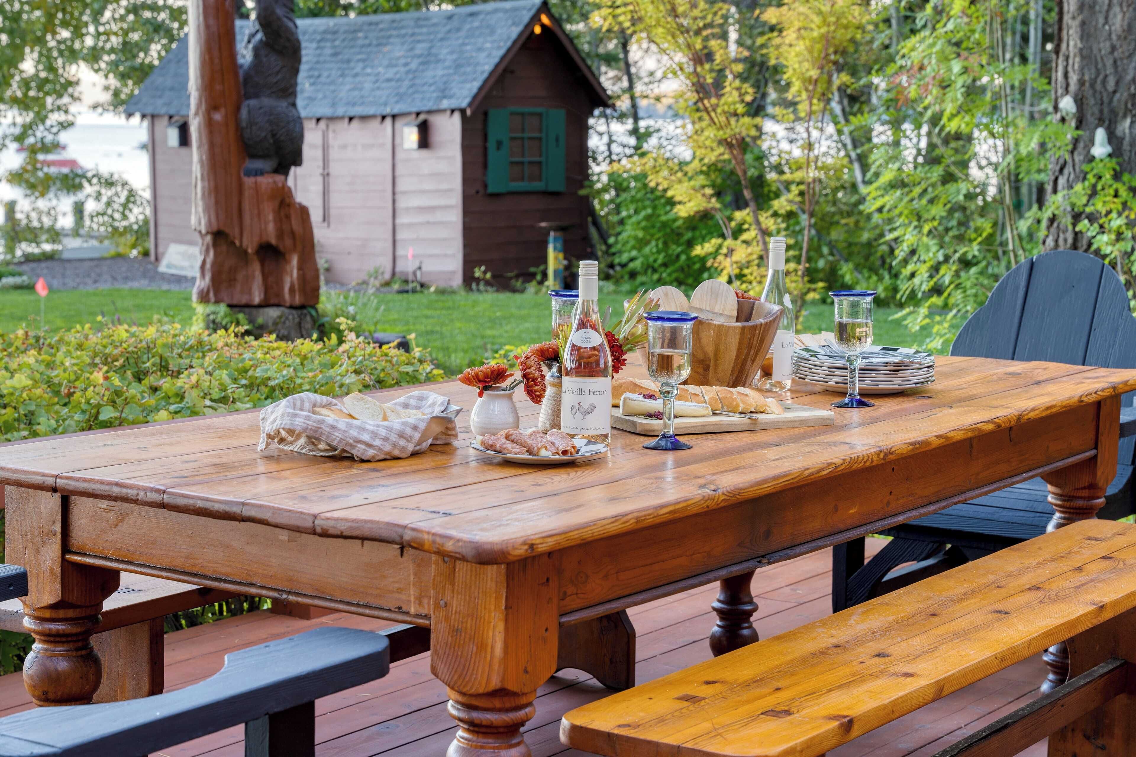 Une table de pique-nique en bois est installée à l’extérieur, avec une cabane rustique en arrière-plan.