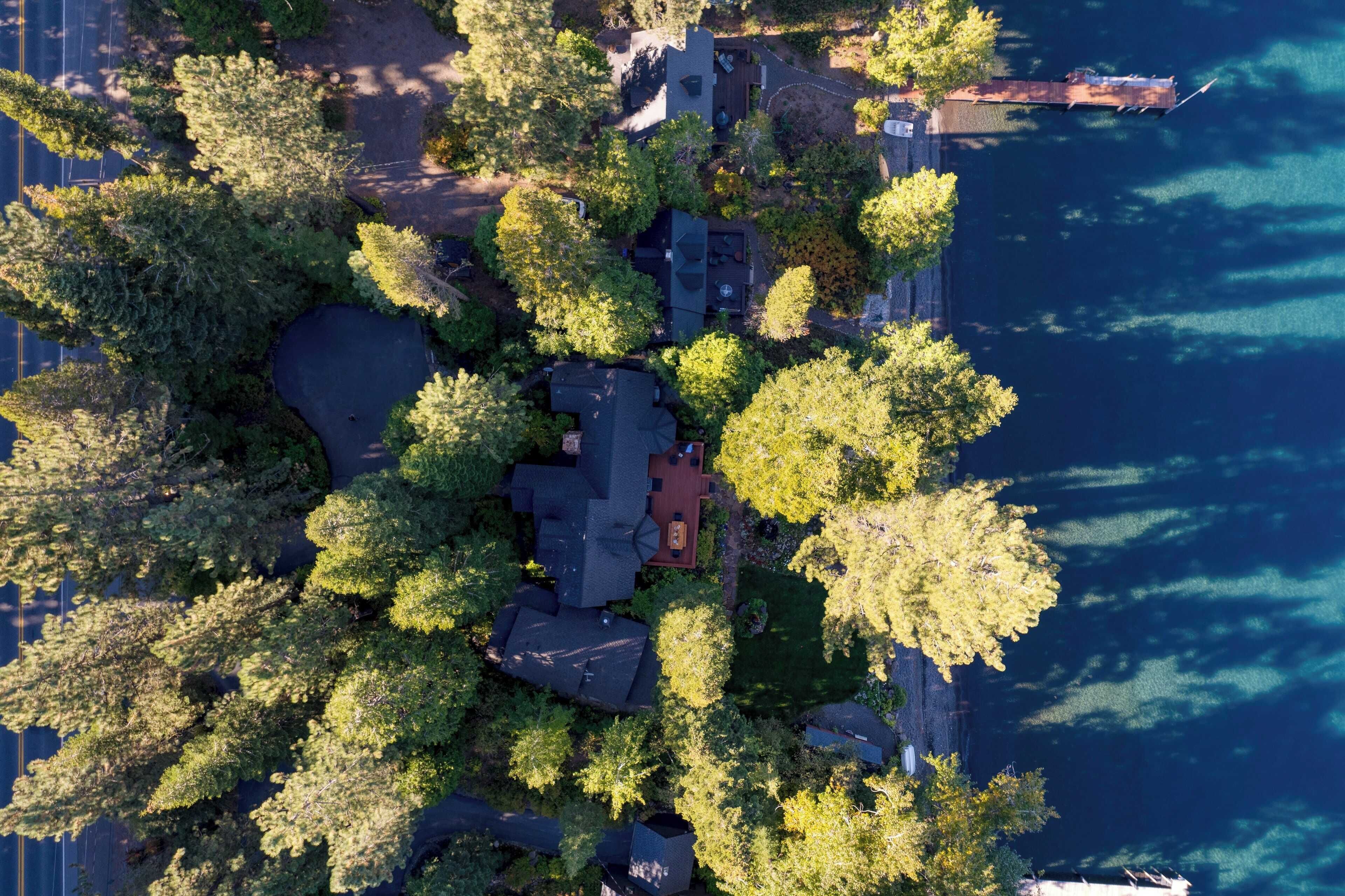 Luchtbeeld van een woongebied met huizen, omringd door dichte begroeiing en een waterpartij.