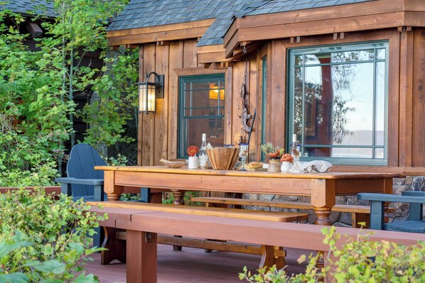 Una baita di legno con una terrazza in legno, un tavolo con panche e una sedia.