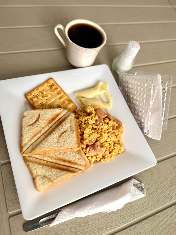 A plate with scrambled eggs, toast, and a cup of coffee on a wooden table.