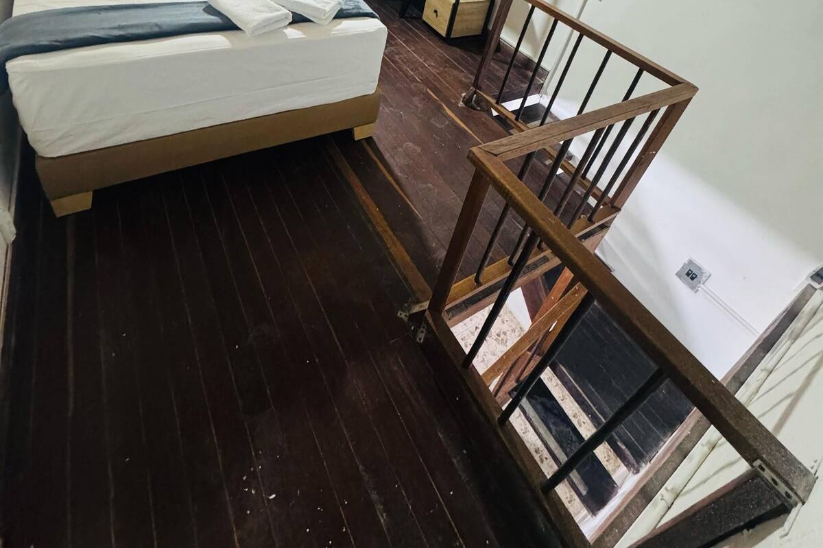 Ein Schlafzimmer mit einem Bett, einem Schreibtisch und einer Holztreppe.
