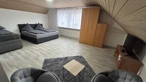 A modern loft bedroom with a bed, sofa, and two armchairs. - Vacation apartment zur Linde II (Altertheim)