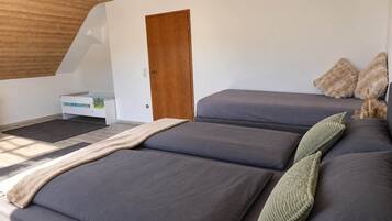 Ein Schlafzimmer mit schrägem Dach, einer Holztür und einem Bett mit vielen Kissen.