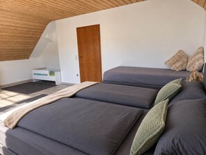 A bedroom with a sloped ceiling, a wooden door, and a bed with multiple pillows. - Vacation Rental at Linde II - 3 Bedrooms (Altertheim)