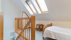 A bedroom with a bed, a wooden stool, a small table, and a wooden staircase. - Ferienwohnung in St. Peter-ording (St. Peter-Ording)