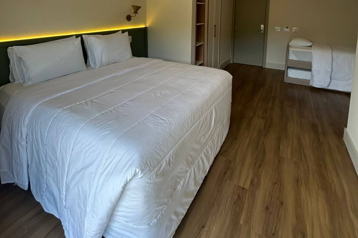 Ein Schlafzimmer mit einem großen Bett, einem Holzkopfteil, einer Nachttischlampe, einem Kleiderschrank und einem kleinen Nachttisch.