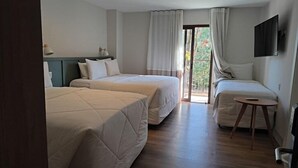 Camera d'albergo con due letti, un tavolino, una TV e vista sull'esterno.