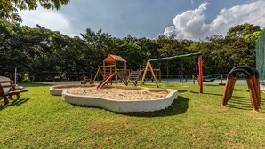 Un'area giochi con sabbiera, altalene e una struttura per arrampicarsi.