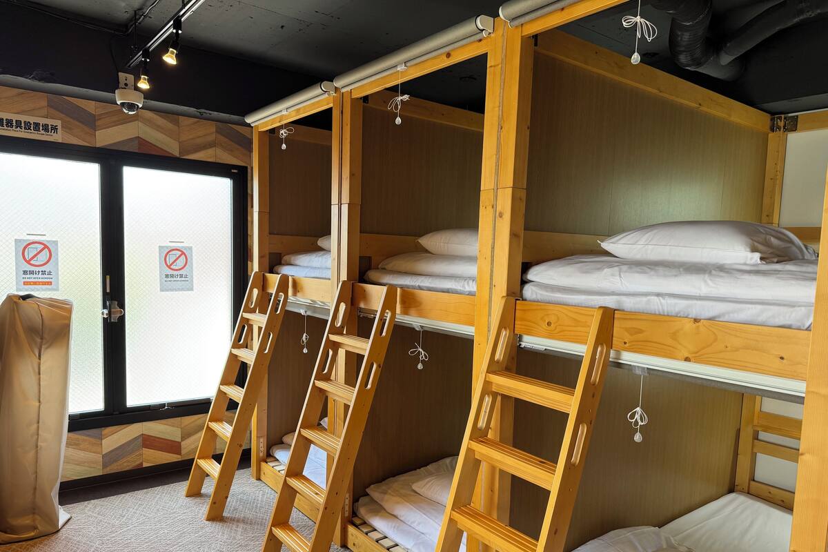 A bunk bed room with wooden ladders and a window with a view.