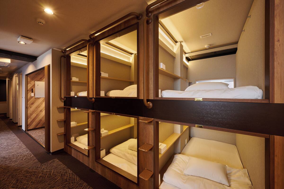 A hotel room with bunk beds, wooden headboards, and built-in shelves.
