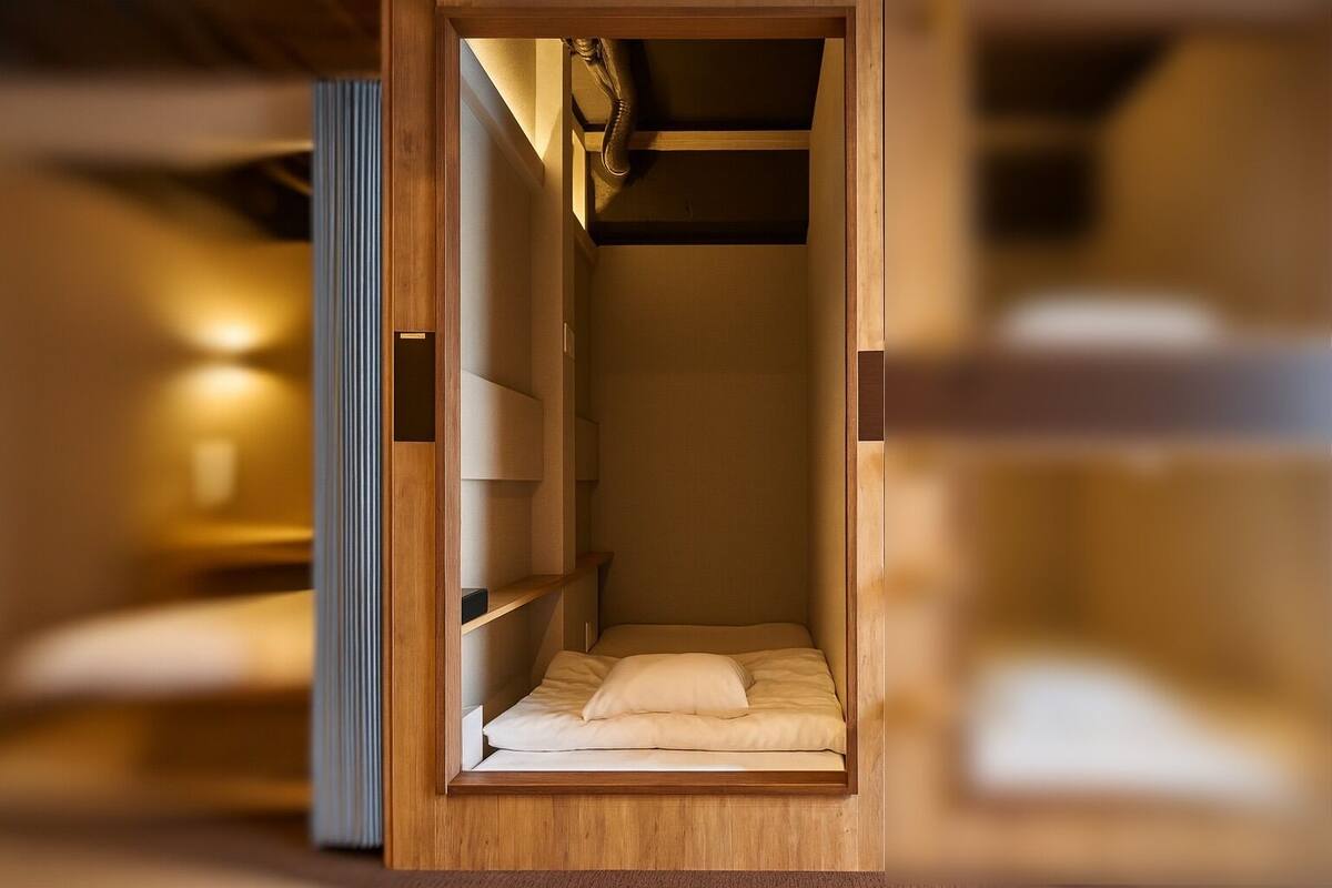A compact, wooden room with built-in shelving and a bed.