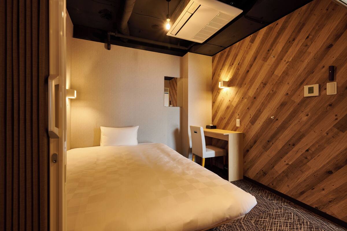 A hotel room with a bed, a desk, and a chair.