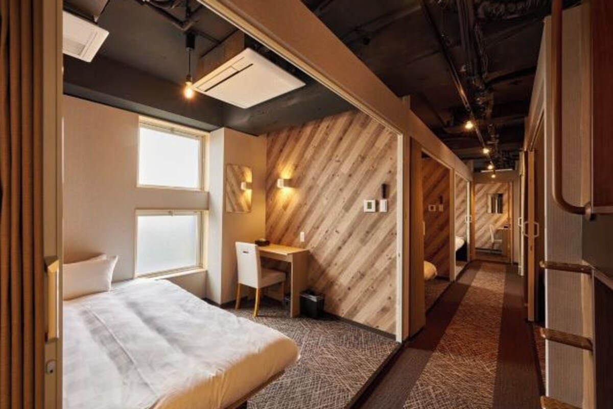 A modern hotel room with a bed, desk, and seating area.