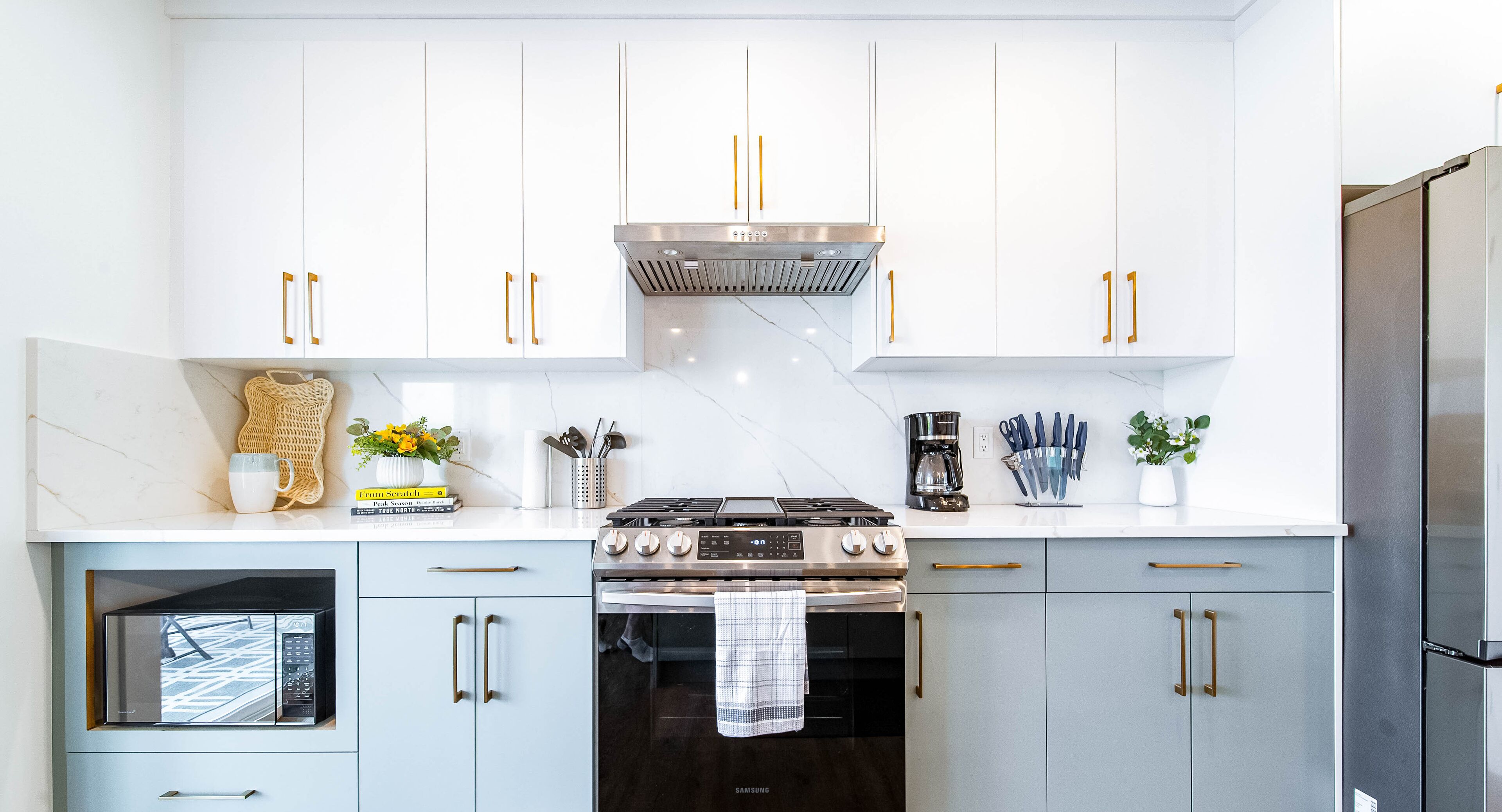 A modern kitchen with white cabinets, a stainless steel stove, and a built-in oven.