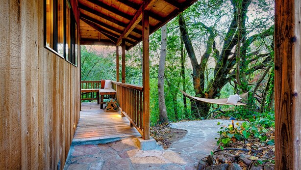 Una terraza de madera con un sendero de piedra que lleva a una hamaca.