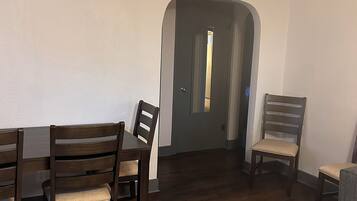 A dining area with a dark wood table and chairs, a patterned rug, and a door leading to another room.
