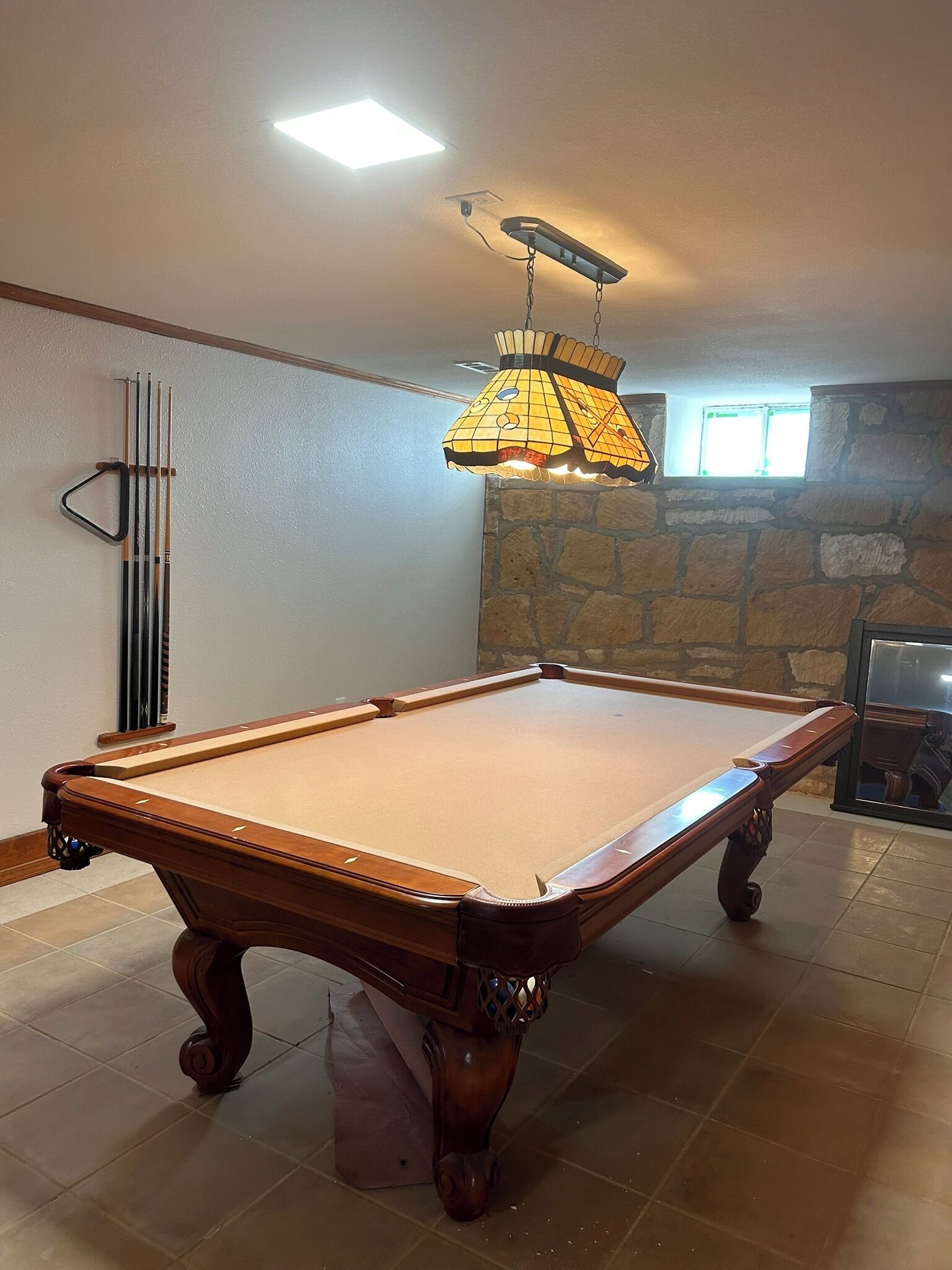 A pool table in a room with a stone wall and a window.