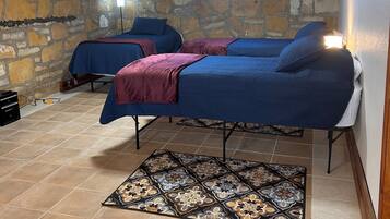 A room with two beds, a stone wall, and a patterned rug.