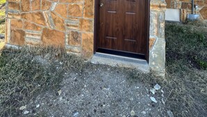 Edifici de pedra amb una porta marró fosc, una petita finestra i una sortida de ventilació metàl·lica al costat superior esquerre.