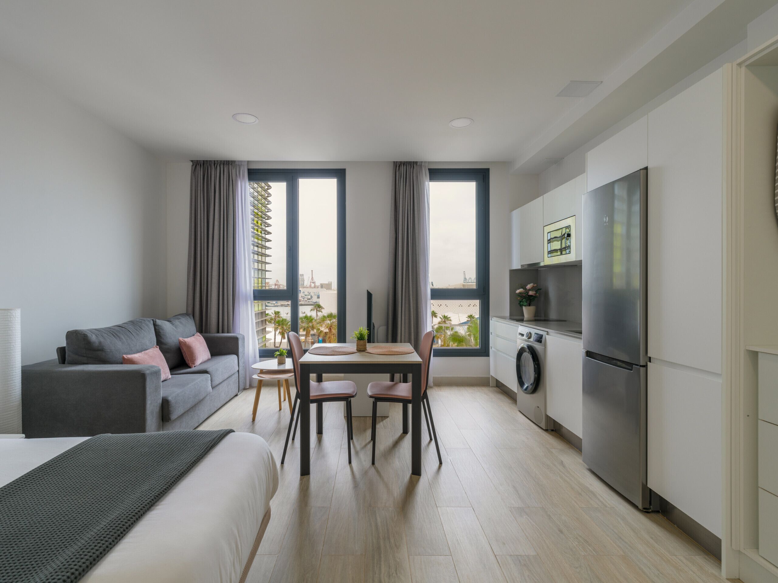 Un apartamento moderno con comedor, kitchenette y un ventanal con vistas a la ciudad.