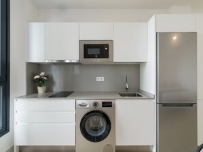 Une cuisine compacte équipée d’un lave-linge, d’un four à micro-ondes et d’un réfrigérateur.