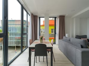 Una sala de estar moderna con sofá, mesa de comedor, sillas y vistas amplias por las ventanas.