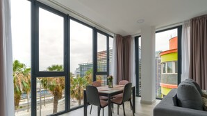 Ein modernes Wohnzimmer mit Essbereich, großen Fenstern und Blick auf die Stadtlandschaft.