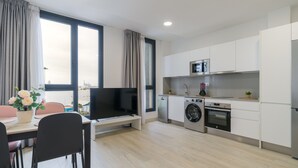Una cocina moderna con televisor de pantalla plana, lavadora, horno y microondas.