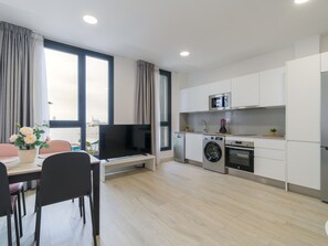 A modern kitchen with a flat-screen TV, washing machine, oven, and microwave.