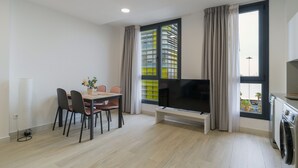 Una sala de estar moderna con comedor, televisor de pantalla plana y lavadora.