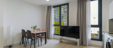 A modern living room with a dining area, a flat-screen TV, and a washing machine.