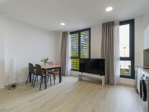 A modern living room with a dining area, a flat-screen TV, and a washing machine.