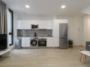 A modern kitchen with white cabinetry, stainless steel appliances, and a built-in oven.