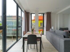 Un salon moderne avec un canapé, une table à manger, des chaises et une vue dégagée grâce à de grandes fenêtres.
