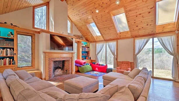 Ein geräumiges Wohnzimmer mit Kamin, großen Fenstern und hohen Decken.