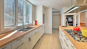 Eine moderne Küche mit einem großen Fenster, einer Spüle, einem Herd und Blick ins Freie.
