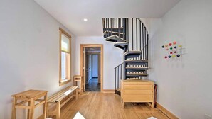 A bedroom with a wooden bed, a small wooden desk, a bench, a spiral staircase, and a wall-mounted color palette. - Home on 40 Acres with Pinball in Game Room (Manchester)
