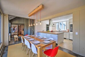 A modern kitchen with a dining area, wooden table, and chairs.