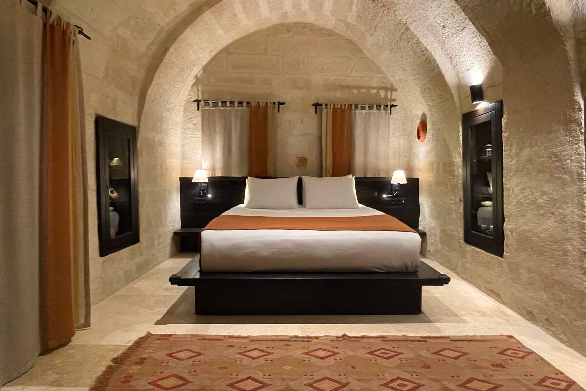 A bedroom with a large bed, two bedside tables, and a patterned rug.